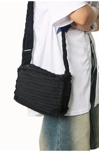 Detail of black canvas crossbody bag with frayed layered design and adjustable strap