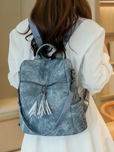 Blue denim texture PU leather backpack with tassel detail shown on model back view