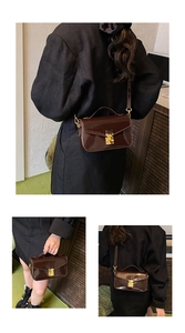 Detail of dark brown patent leather square bag with gold buckle and top handle