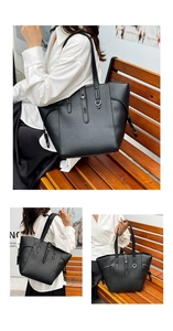 Detail of large black tote bag with grain leather texture and metallic buckle strap