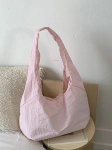 Pink large capacity minimalist tote bag with wide shoulder strap on wooden table