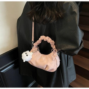 Détail du sac rose avec poignée plissée, gaufrage et breloque en peluche sur le modèle