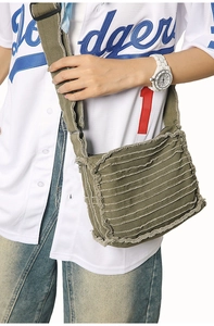 Close-up of military green canvas crossbody bag with frayed edges and industrial texture
