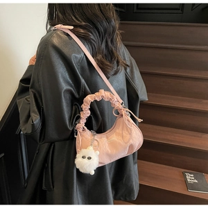 Sac à main plissé rose avec anse nuage et pendentif peluche porté par un mannequin