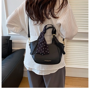 Détail du sac à main noir texturé litchi avec lettrage doré et foulard à pois
