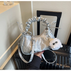 Détail du sac à main argenté texturé plissé avec nœuds coulissants et breloque en peluche