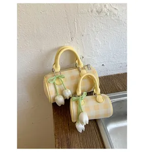 Detail of yellow checkered cylinder bags with tulip floral charms on wood surface