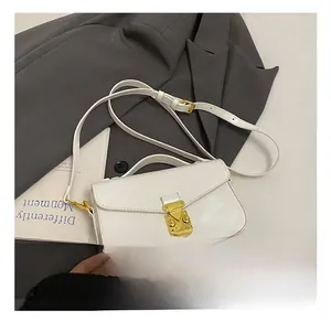 Detail of white glossy leather handbag with gold metal clasp and adjustable strap