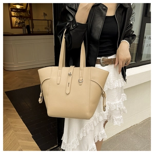 Close-up of a beige large-capacity tote bag with pebbled leather texture and metal buckle