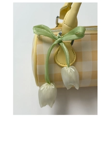 Detail of yellow checkered Boston bag with tulip charms and green satin ribbon bow
