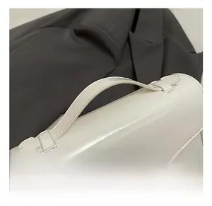 Detail of comfortable white patent leather handle with gold metal lock on square bag