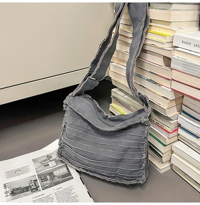 Detail shot of a grey canvas crossbody bag with distressed frayed edges on vintage books