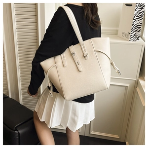Detail of beige lychee grain leather tote bag with side drawstring and shoulder strap