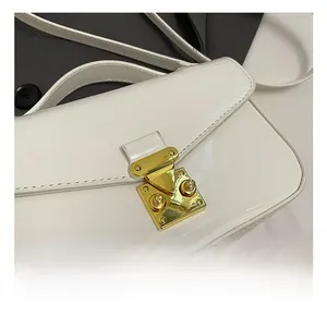 Detailed close-up of premium gold-toned metal clasp on glossy white patent leather bag