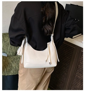 Close-up of off-white hobo bag with lychee texture leather and decorative tassel