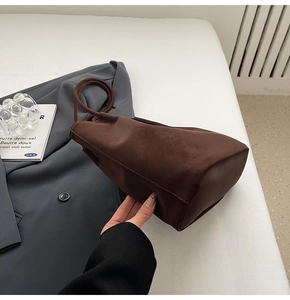 Detail of soft matte dark brown suede tote bag styled with a grey business suit