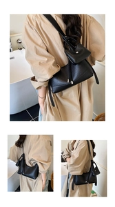 Close-up of minimalist black pebble leather crescent bag with adjustable strap and coin pouch