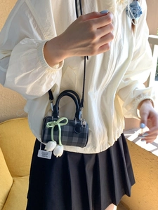 Chic grey checkered cylinder crossbody bag with tulip pendant worn by model
