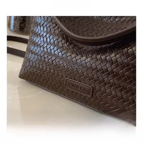 Close-up of dark brown woven leather bucket bag texture with brand logo detail