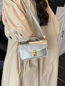Silver mirror leather crossbody bag with gold buckle and chain strap on female model