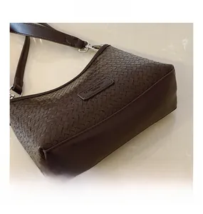 Detailed view of dark brown woven texture and silver hardware on a bucket shoulder bag