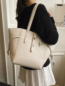 Chic beige lychee leather tote bag with silver buckle worn by model in minimalist interior