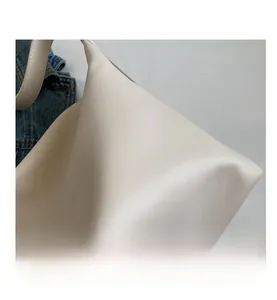 Close-up of white tote bag showing smooth matte leather texture and premium stitching
