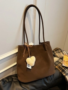 Vintage dark brown faux suede tote bag with heart charm and bow in home setting