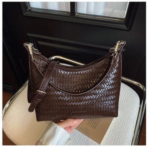 Detail of dark brown woven texture bucket bag with adjustable strap and silver buckle