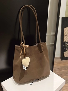 Coffee brown suede hobo tote bag with plush heart charm on a minimalist white stand