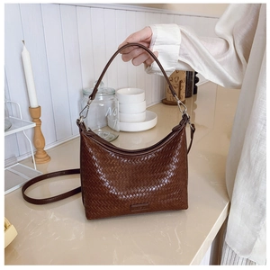 Macro view of woven brown leather texture and silver buckle on bucket shoulder bag