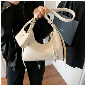 Close-up of off-white lychee grain leather crescent bag with silver hardware and mini pouch