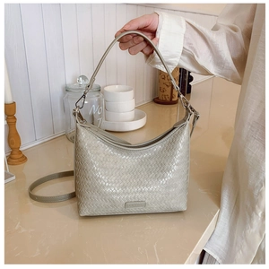 Detail of grey woven texture bucket bag with adjustable shoulder strap in a home setting