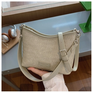 Detailed close-up of woven texture and silver buckle on light greyish-green bucket bag