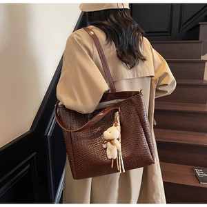 Detail of dark brown woven tote bag with a cute plush bear pendant and soft texture