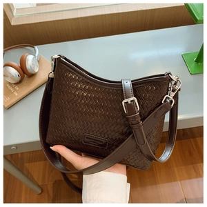 Detail shot of a dark brown woven texture bucket bag with a slim adjustable shoulder strap