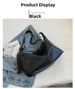 Detail view of black vintage leather hobo bag with gold buckle on denim jacket
