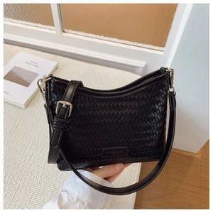 Detail of black woven bucket bag showing tight knit texture and adjustable leather strap