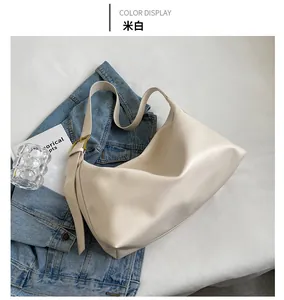 Detail view of cream white soft PU leather hobo bag with gold hardware on white fabric