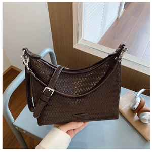 Close-up of dark brown woven bucket bag featuring detailed leather texture and silver buckle