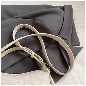 Détail du sac seau crème minimaliste montrant le cuir à motif litchi et la boucle