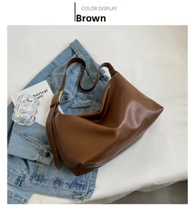 Close-up of brown faux leather shoulder bag with gold metal buckle on denim jacket