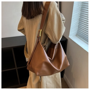 Close-up of caramel leather hobo bag with wide adjustable strap and gold metal buckle