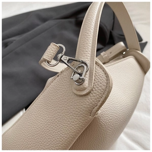 Détail du sac seau en cuir litchi crème avec crochet pivotant en métal argenté et coutures