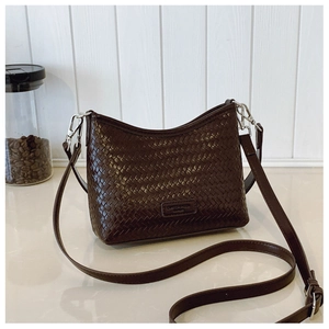 Close-up of deep brown woven bucket bag featuring detailed leather texture and metal buckle