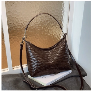 Detailed view of the woven dark brown bucket bag with metallic hardware and adjustable strap