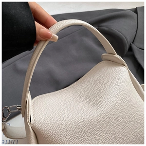 Vue détaillée du cuir beige à texture litchi avec maillon en métal argenté sur le sac seau