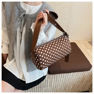 Detailed view of the brown polka dot pillow bag with leather shoulder strap and metal zipper