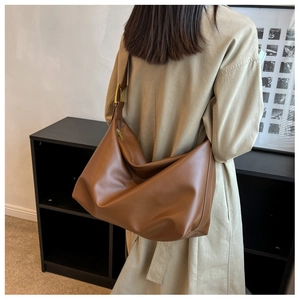 Detail view of large brown hobo bag with wide shoulder strap and gold-tone metal buckle