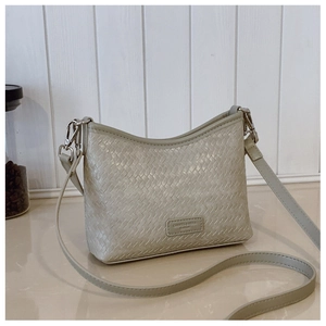 Close-up of woven texture and metal logo plaque on a light green bucket shoulder bag